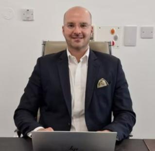 Dr. Hazim Sadideen, Consultant Plastic, Reconstructive, and Aesthetic Surgeon, sitting at his desk.