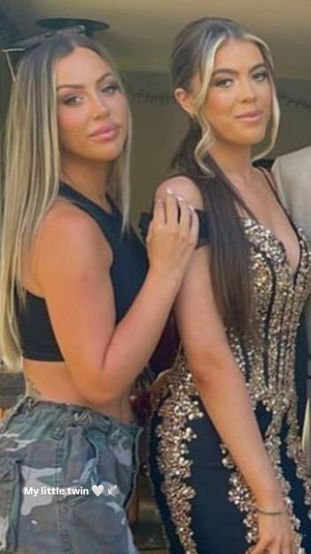 Two young women posing, with one wearing a black top and camouflage pants and the other in a black and gold sequined dress.
