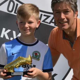 Boy holding a golden shoe award with a man.