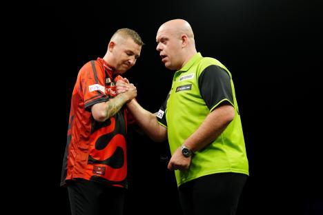 Nathan Aspinall and Michael van Gerwen shaking hands after a darts match.