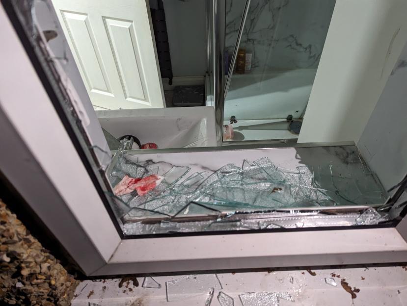 Broken glass from a shattered window, with a piece of cloth with blood on it, in Grace's home after being broken into.
