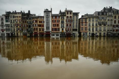 Flooded buildings reflected in muddy water.