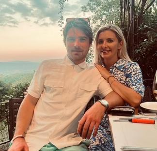 Couple sitting at an outdoor table with a scenic view.