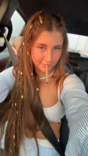Selfie of a young woman smoking a joint in a car.