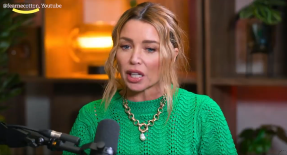 Woman in green sweater speaking into a microphone.