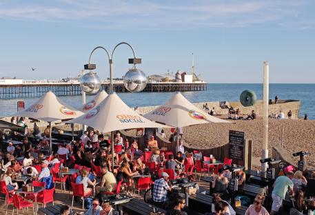 Busy beachside restaurant with pier in background.