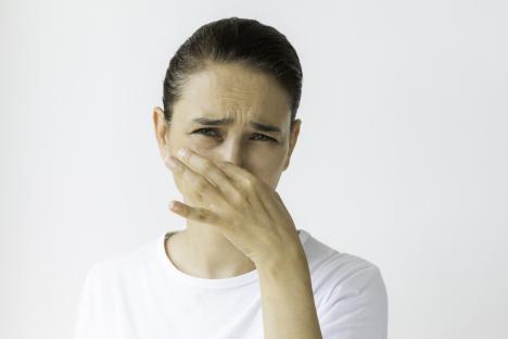 Woman holding her nose, looking disgusted.