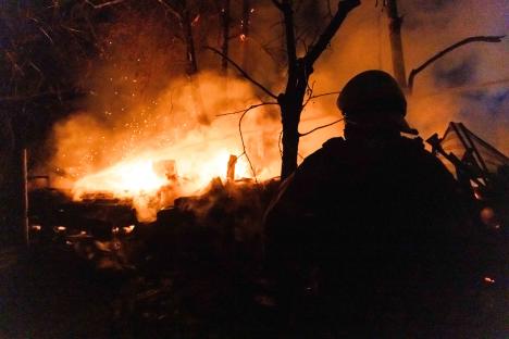 Firefighter silhouetted against a large fire.