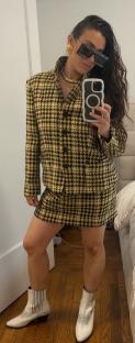 Woman in a yellow and black houndstooth suit and white cowboy boots.