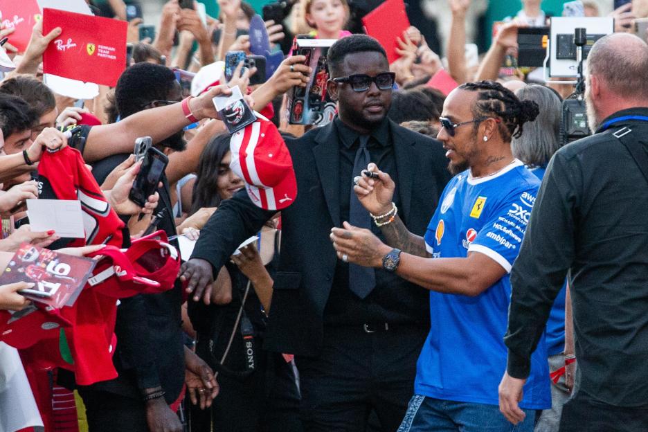 Lewis Hamilton signing autographs for Ferrari fans.