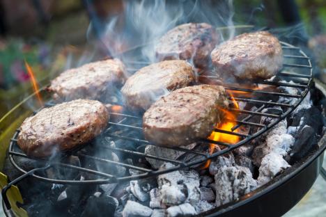 Burgers cooking on a charcoal grill.