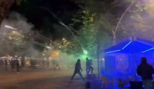 Real Betis and Fiorentina fans clashing amidst smoke and fireworks.