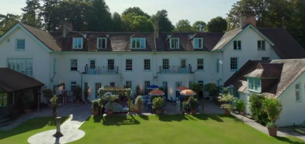 Aerial view of a large white house with a patio and garden.