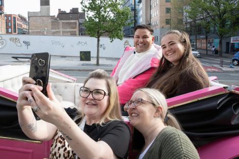 A group of people taking a selfie in a pink carriage.