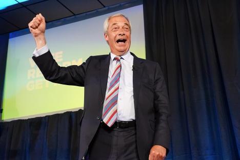Nigel Farage celebrating on stage after Reform UK's election win.