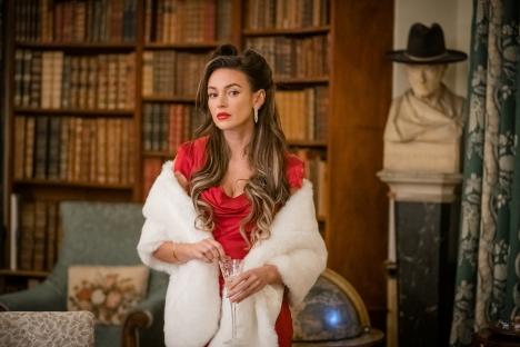 Michelle Keegan in a red dress and white fur stole, holding a glass.