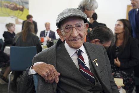 A man in a suit and cap at a VE Day anniversary tea party.