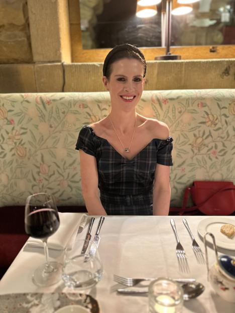 Woman in a plaid dress sitting at a table set for dinner.