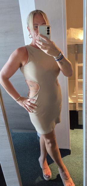 Woman in beige cutout dress taking a mirror selfie.