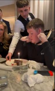 A young man celebrating his birthday with a chocolate cake.