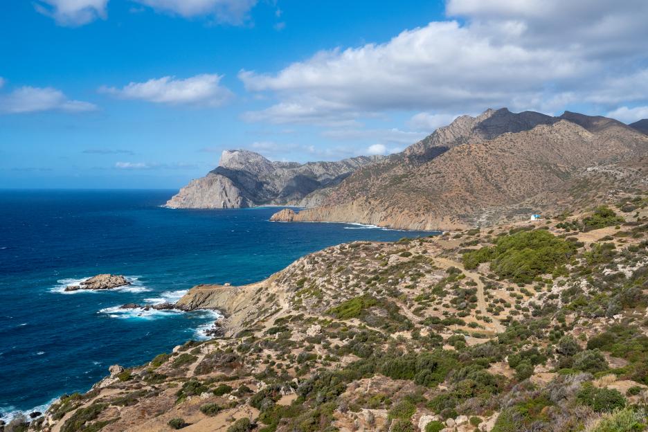 Coastal landscape of Karpathos island, Greece, with rocky cliffs and turquoise waters under a blue sky.