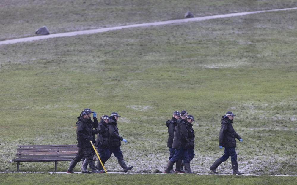 A group of police officers are walking across a grassy field