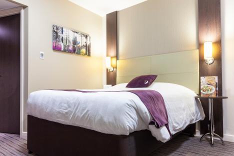 Hotel room with double bed and bedside table.