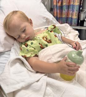 Toddler sleeping in a hospital bed with an IV.