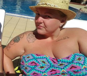 Woman in a patterned swimsuit by a pool.