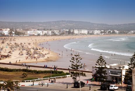 Essaouira beach in Morocco, with many people sunbathing and swimming.