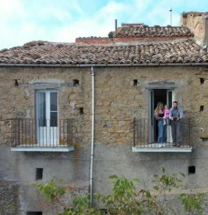 Family standing on balcony of Italian house.