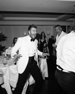 Black and white photo of David Beckham laughing and dancing at a party.