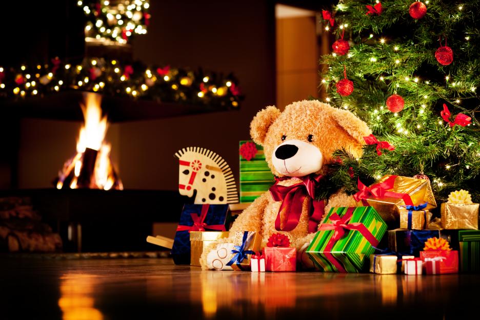 Christmas presents under a decorated tree near a fireplace.
