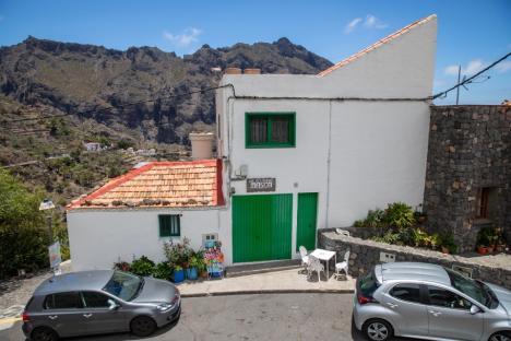 White building with green doors in a mountainous area.