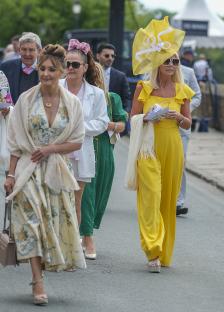 Women in stylish outfits at a racecourse.