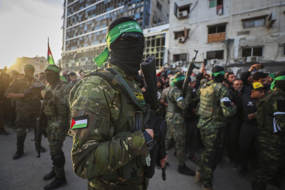 Fighters from the Qassam Brigades control a crowd as the Red Cross collects Israeli hostages in Gaza City.