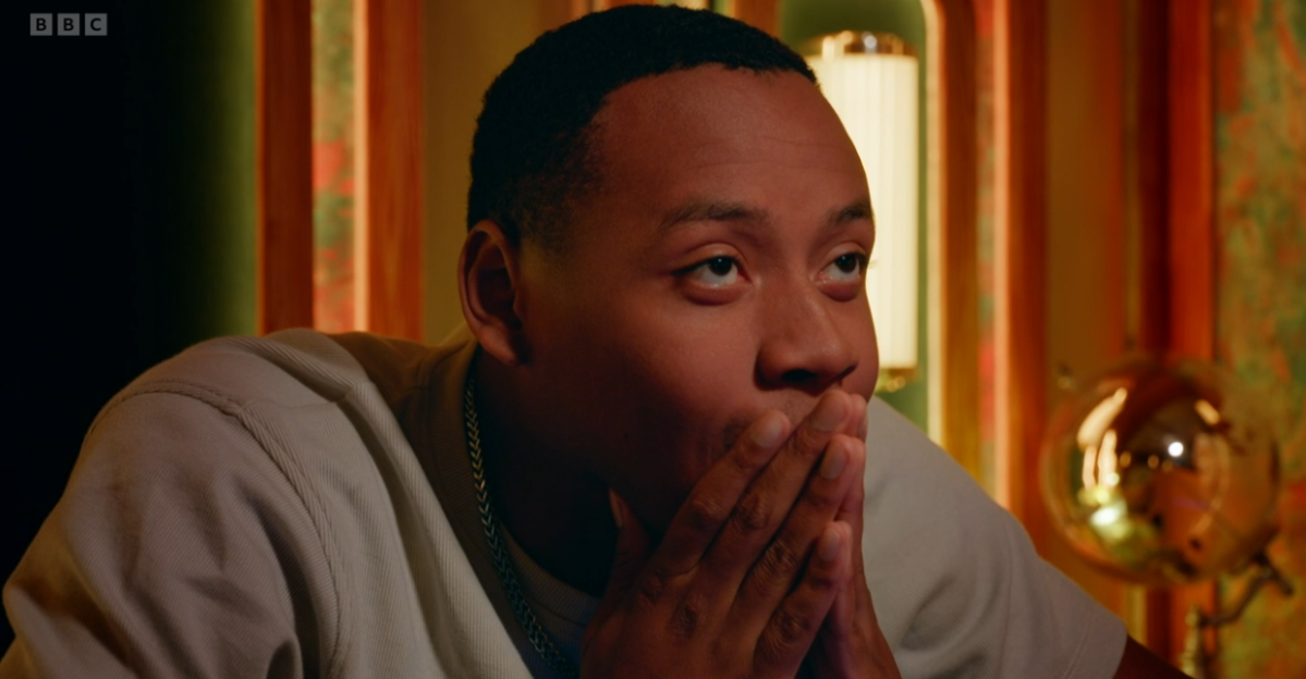 A man looking shocked and covering his mouth with his hands.