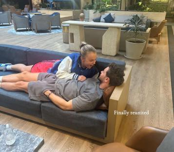Couple reunited on a couch in a hotel lobby.