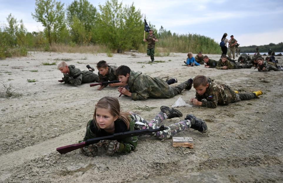 Students in camouflage uniforms participate in military training exercises.