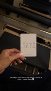 Photo of a hand holding a card with a quote about self-love, taken in a Pilates studio.