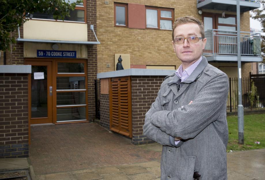 Ryan Edwards stands outside 59-70 Cooke Street, Stephen Port's flat, with his arms crossed.