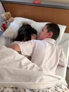 A boy and girl cuddling in bed.