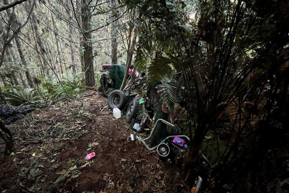 Photo of a campsite in the woods, with an ATV and other items.