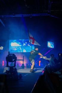 A strongman carrying a British flag after a competition.