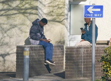 Two migrants using cell phones at a former RAF base.