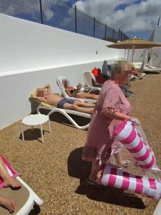 A woman confronts sunbathers at a poolside.