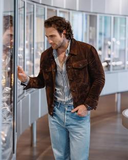 Aaron Taylor-Johnson looking at watches in a display case.