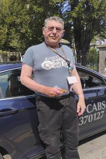 A taxi driver standing next to his cab.