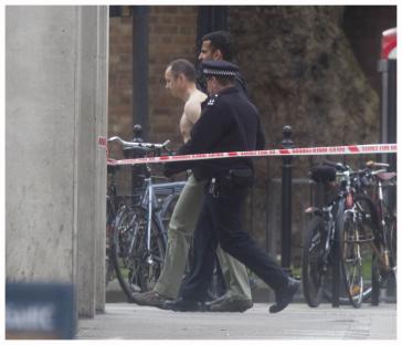 A man being led away by police.