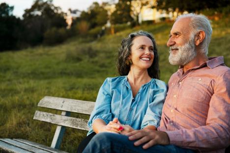 Smiling senior couple sitting on a park bench.